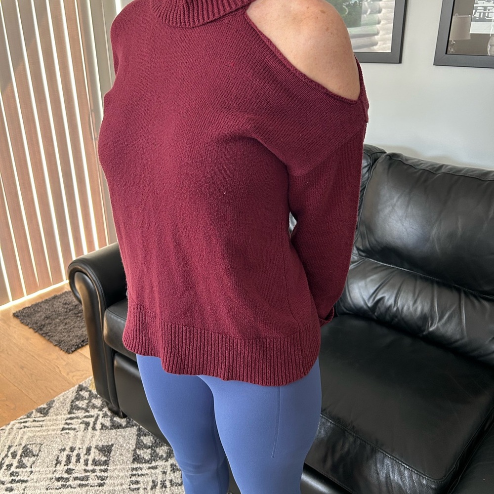 Woman’s turtleneck sweater with cuffed sleeves and a “cold shoulder” on the left